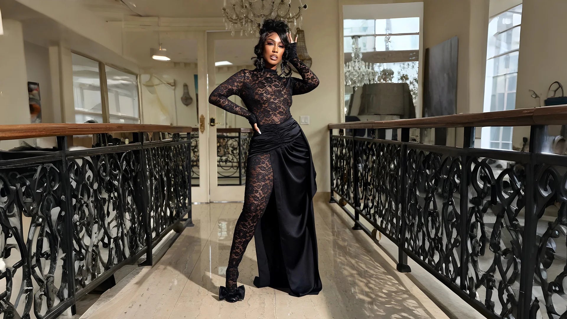 Woman in a black lace dress standing in an elegant interior setting